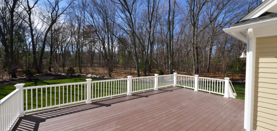 New,backyard,deck.,white,vinyl,railings,and,composite,brown,boards.